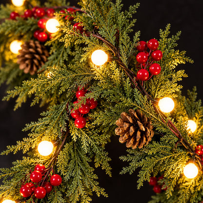 Detailed close-up of lit Christmas garland, red berries, cedar-like foliage and brown pinecones