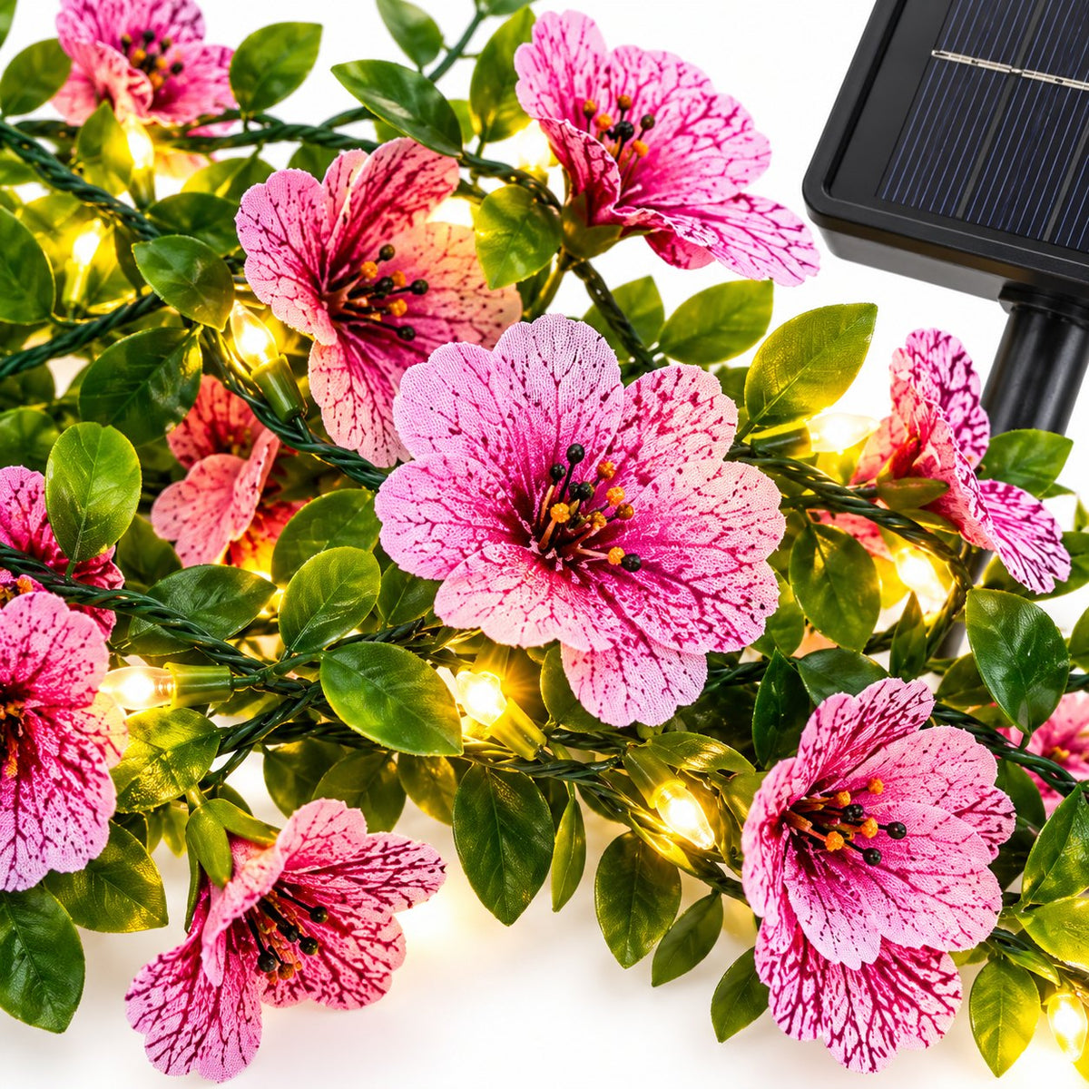 Close-up of pink violet artificial flowers, green leaves and glowing fairy lights